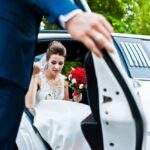 groom open door of limousine and take hand to bride
