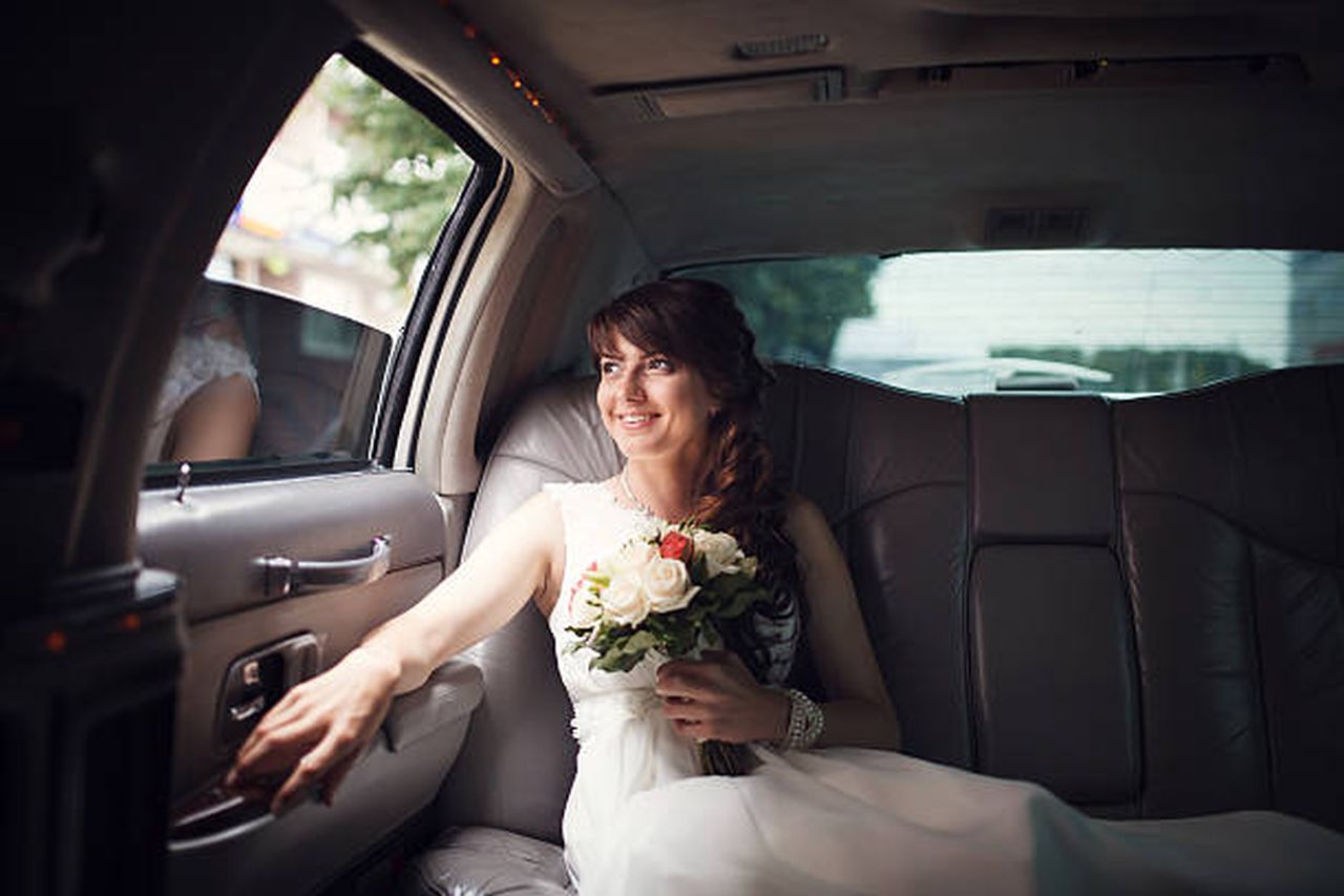smiling bride looking out the window of the car