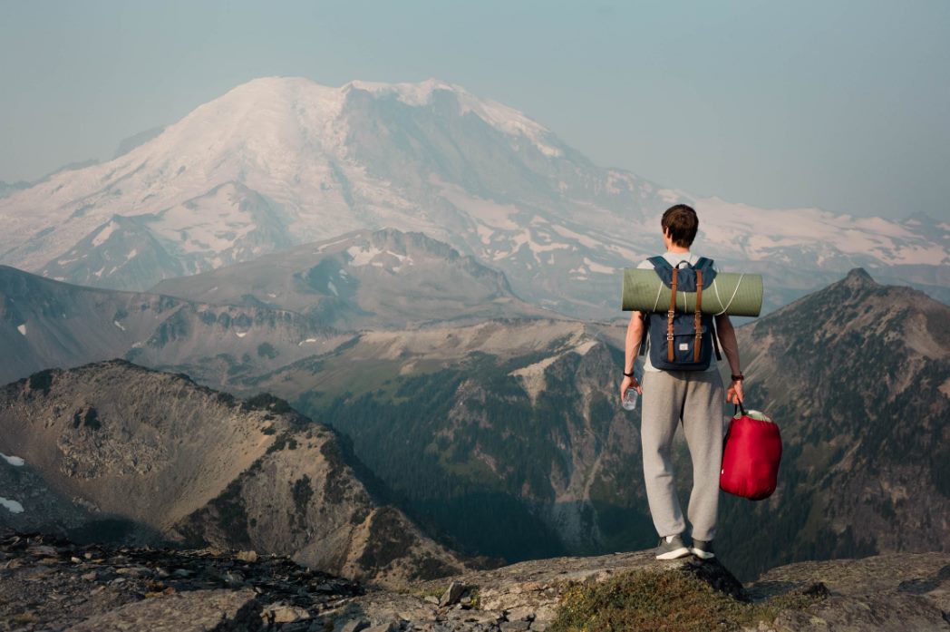 unrecognizable backpacker standing on top of mount